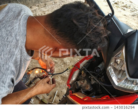 man changing wheel on a motorcycle man changing wheel on a motorcycle 143016294