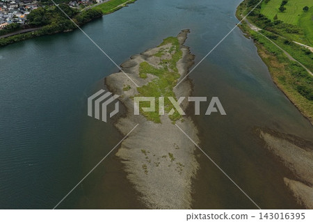 An aerial photograph capturing a sandbar in the Shimanto River and a residential area in Shimanto City, Kochi Prefecture. 143016395