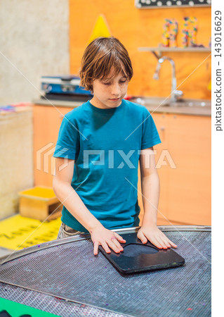 Boy experimenting with hands on science activity in a learning space indoors with interactive equipment STEM education curiosity creative play concentration and close up. 143016629