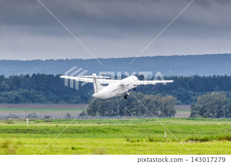 White passenger turboprop airplane takes off runway in cloudy weather White passenger turboprop airplane takes off runway in cloudy weather 143017279