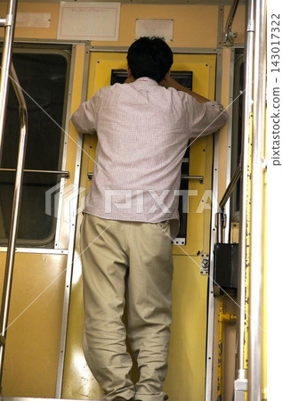 The back view of a man standing inside a train car near the coupling section. The back view of a man standing inside a train car near the coupling section. 143017322