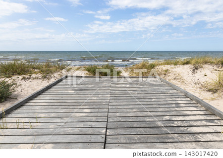 Wooden boardwalk leading to the sandy beach and sea Wooden boardwalk leading to the sandy beach and sea 143017420