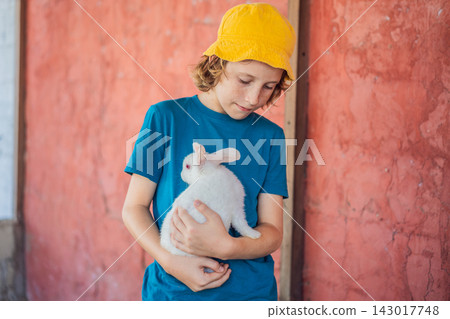 Child holds a white rabbit close during a petting zoo visit. Gentle handling and learning about pet care. Child holds a white rabbit close during a petting zoo visit. Gentle handling and learning about pet care. 143017748