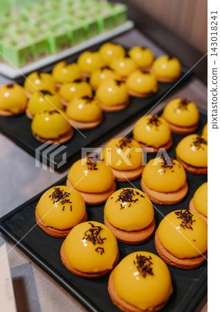 Yellow glazed pastries with chocolate sprinkles on black trays Yellow glazed pastries with chocolate sprinkles on black trays 143018241
