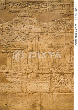 Ancient Egyptian relief carving on weathered stone wall 143018538