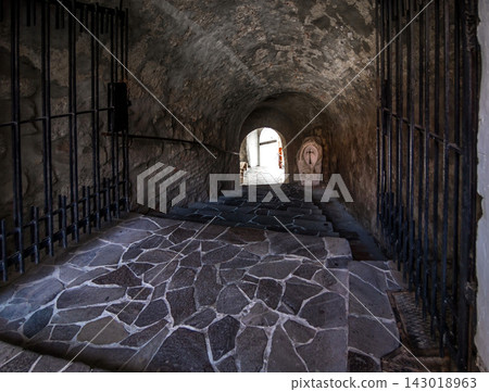 Passage between two parts of the ancient castle with an old stone staircase. Stone arch and steps in the castle. Stone corridor with stairway in ancient castle. Passage between two parts of the ancient castle with an old stone staircase. Stone arch and steps in the castle. Stone corridor with stairway in ancient castle. 143018963