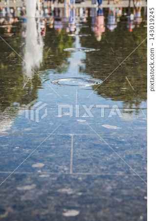 Water ripples on dark blue granite tiles in urban public plaza Water ripples on dark blue granite tiles in urban public plaza 143019245