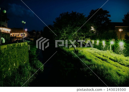 Night park scene with canal and illuminated grass paths Night park scene with canal and illuminated grass paths 143019300