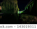 Weeping willow tree and concrete bridge over river at night 143019311