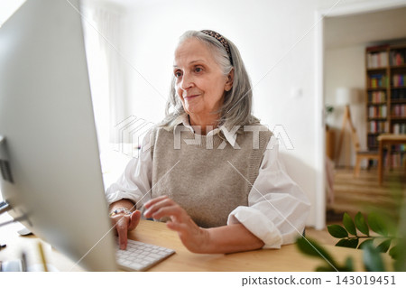 Mature professional woman continuing her career while working from home. Mature professional woman continuing her career while working from home. 143019451
