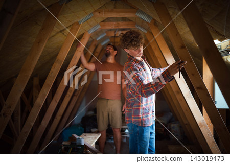 Father teaching teenage son DIY skills while renovating attic together. Father teaching teenage son DIY skills while renovating attic together. 143019473