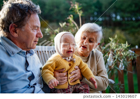 Grandparents holding baby in warm embrace during fall season. Grandparents holding baby in warm embrace during fall season. 143019607