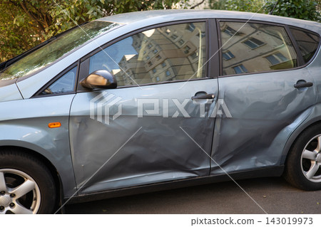Damaged silver car with heavily dented side doors after a traffic accident. Damaged silver car with heavily dented side doors after a traffic accident. 143019973