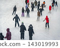 Crowded Outdoor Ice Rink Viewed From Above. High-angle view, numerous people skating across broad winter ice rink. Busy public recreation, seasonal activity, urban leisure. Winter sport background 143019993