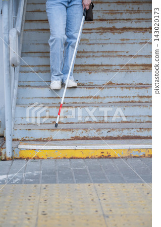 A blind woman descends a staircase. Close-up of her feet and a tactile stick. A blind woman descends a staircase. Close-up of her feet and a tactile stick. 143020173