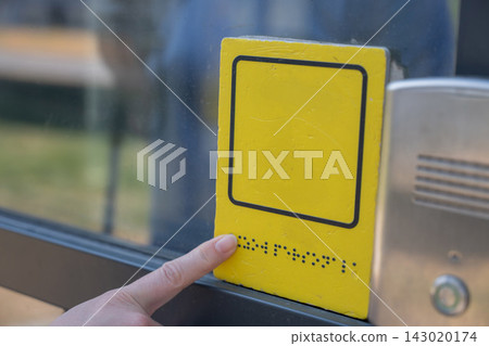 A blind woman reads the braille sign next to a call button. A blind woman reads the braille sign next to a call button. 143020174