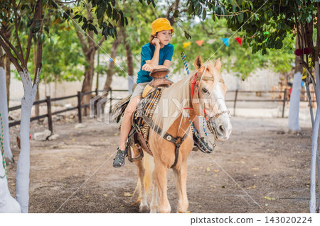 Child spends leisure time horseback riding at a farm. Outdoor recreation and family farm leisure. Child spends leisure time horseback riding at a farm. Outdoor recreation and family farm leisure. 143020224