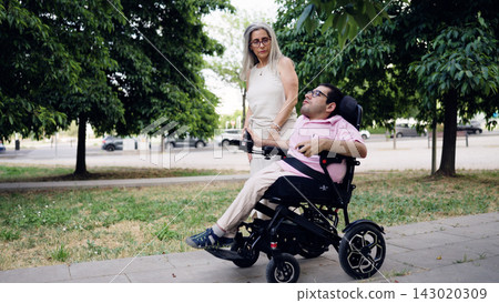 Man with spina bifida using motorized wheelchair with caregiver Man with spina bifida using motorized wheelchair with caregiver 143020309