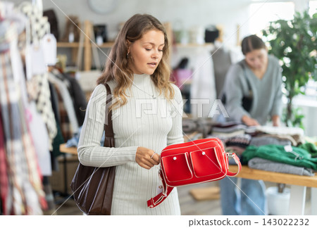 Selective young girl choosing handbag in clothing store Selective young girl choosing handbag in clothing store 143022232