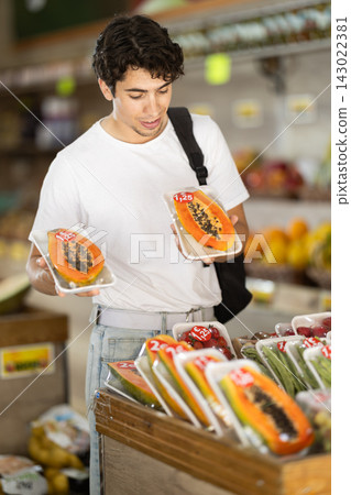 Male customer choosing vegetables and fruits in packaging at grocery store Male customer choosing vegetables and fruits in packaging at grocery store 143022381