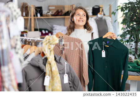 Young woman chooses warm dress in clothing store 143022435
