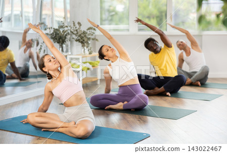 Group of men and women doing yoga in studio Group of men and women doing yoga in studio 143022467