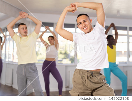 Happy multinational young man and woman dancing and training latin dance movements in ballroom together Happy multinational young man and woman dancing and training latin dance movements in ballroom together 143022508