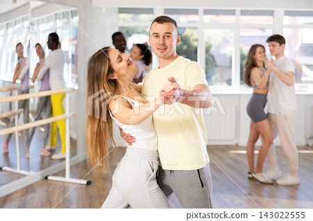Young man and woman practicing tango dance in pair in training hall Young man and woman practicing tango dance in pair in training hall 143022555