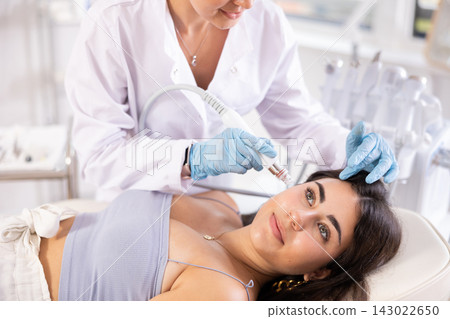 Young woman undergoing facial cosmetic treatment using ion bubble pen Young woman undergoing facial cosmetic treatment using ion bubble pen 143022650
