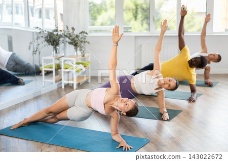 Group of men and women doing pilates in studio Group of men and women doing pilates in studio 143022672