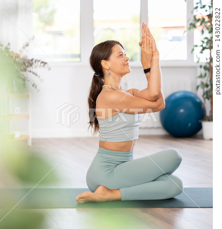 Experienced girl fitness club teacher performs cow head asana, gomukhasana Experienced girl fitness club teacher performs cow head asana, gomukhasana 143022822