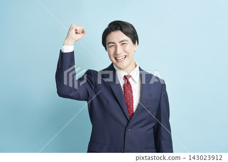 A businessman making a victory pose against a light blue background. A businessman making a victory pose against a light blue background. 143023912