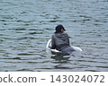 A man and a girl, both wearing swimsuits and backpacks, are swimming in the bay. A man and a girl, both wearing swimsuits and backpacks, are swimming in the bay. 143024072