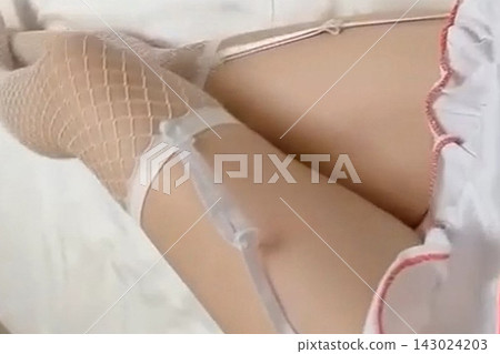 一名身穿緊身衣的女子躺在床上。 143024203