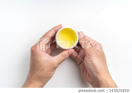 Top view of hands holding small ceramic cup of hot oolong tea isolated on white background with copy space Top view of hands holding small ceramic cup of hot oolong tea isolated on white background with copy space 143025859