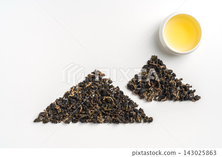 Top view of loose oolong tea leaves arranged in mountain shape with tea cup isolated on white background with copy space 143025863