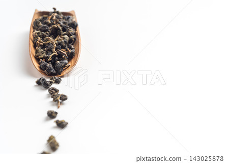 Close up of loose oolong tea leaves on wooden holder with selective focus isolated on white background with copy space Close up of loose oolong tea leaves on wooden holder with selective focus isolated on white background with copy space 143025878