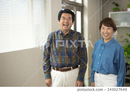 A senior couple smiling in their living room A senior couple smiling in their living room 143027649