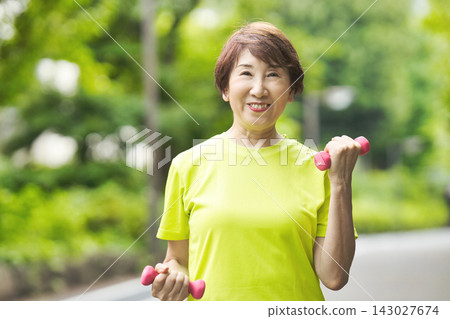 一位微笑的老婦人手持粉紅色啞鈴。 143027674