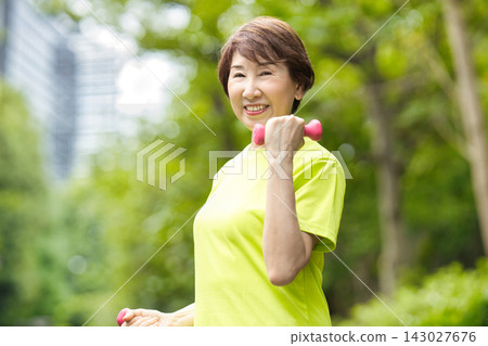 一位微笑的老婦人手持粉紅色啞鈴。 143027676