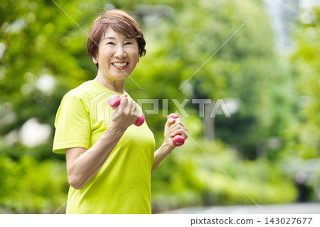 一位微笑的老婦人手持粉紅色啞鈴。 一位微笑的老婦人手持粉紅色啞鈴。 143027677
