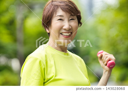 一位微笑的老婦人手持粉紅色啞鈴。 一位微笑的老婦人手持粉紅色啞鈴。 143028068