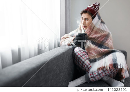 Man freezing at home amidst central heating failure and energy crisis. High energy costs make indoor life cold and shivering. Discomfort in winter. Shivering indoors. Man freezing at home amidst central heating failure and energy crisis. High energy costs make indoor life cold and shivering. Discomfort in winter. Shivering indoors. 143028291