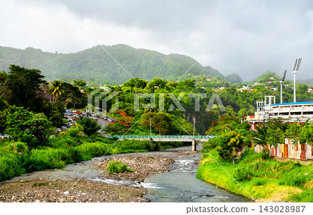 Scenic view of the Roseau River flowing through lush green hills toward Windsor Park Stadium in Roseau, Dominica. Scenic view of the Roseau River flowing through lush green hills toward Windsor Park Stadium in Roseau, Dominica. 143028987