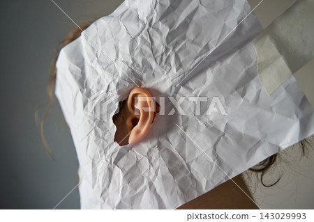 Side Of Head Wrapped In Crumpled White Paper With Ear Visible Through Torn Opening Side Of Head Wrapped In Crumpled White Paper With Ear Visible Through Torn Opening 143029993