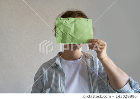 Crumpled Green Squared Sheet Held Across Face By Woman In Open Striped Shirt, With Bent Paper Edges Crumpled Green Squared Sheet Held Across Face By Woman In Open Striped Shirt, With Bent Paper Edges 143029996