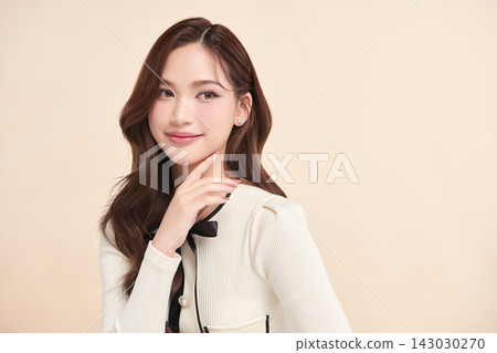 A beautiful young Asian woman with clean, fresh skin against a beige background. Skincare, facial treatment, cosmetology, beauty, and spa. An elegant portrait of an Asian woman. A beautiful young Asian woman with clean, fresh skin against a beige background. Skincare, facial treatment, cosmetology, beauty, and spa. An elegant portrait of an Asian woman. 143030270