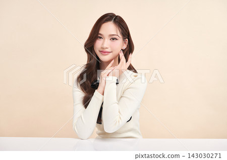 A beautiful young Asian woman with clean, fresh skin against a beige background. Skincare, facial treatment, cosmetology, beauty, and spa. An elegant portrait of an Asian woman. A beautiful young Asian woman with clean, fresh skin against a beige background. Skincare, facial treatment, cosmetology, beauty, and spa. An elegant portrait of an Asian woman. 143030271