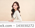 A beautiful young Asian woman with clean, fresh skin against a beige background. Skincare, facial treatment, cosmetology, beauty, and spa. An elegant portrait of an Asian woman. 143030272