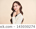 A beautiful young Asian woman with clean, fresh skin against a beige background. Skincare, facial treatment, cosmetology, beauty, and spa. An elegant portrait of an Asian woman. 143030274